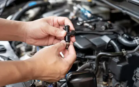 Mani che tengono un iniettore auto, componente essenziale per il funzionamento del motore.