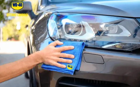 Mano che lucida fari auto con WD-40 e panno blu. Ottimo lavoro!