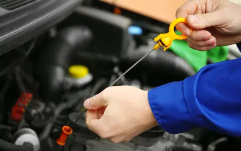 Controllo livello olio motore. La mano estrae l'astina per verificare la presenza di perdita olio motore.
