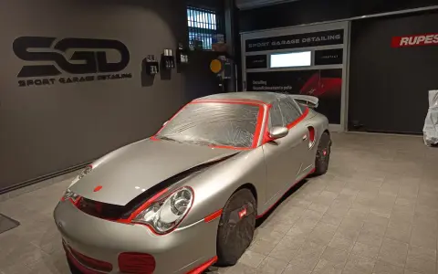 Auto sportiva pronta per la verniciatura, con protezioni rosse e cellophane. Il logo "SGD Sport Garage Detailing" è visibile.