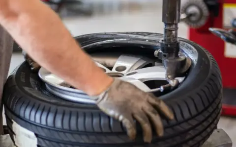 Un meccanico lavora su una gomma. La domanda su ogni quanti km si cambiano le gomme è importante per la sicurezza.