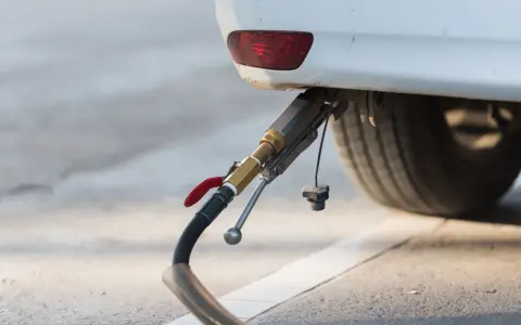 Rifornimento di un'auto a gas. Il tubo di erogazione è collegato all'attacco, pronto per il pieno. GPL e metano sono la stessa cosa per molti, ma non è così.