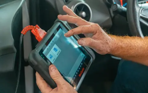 Un meccanico usa uno scanner per scoprire quanto costa una diagnosi auto.
