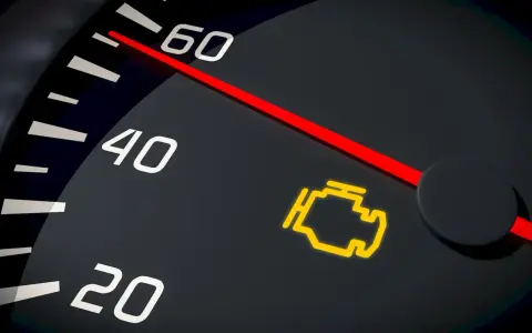 Cruscotto auto con spia motore accesa, indicatore rosso su tachimetro.