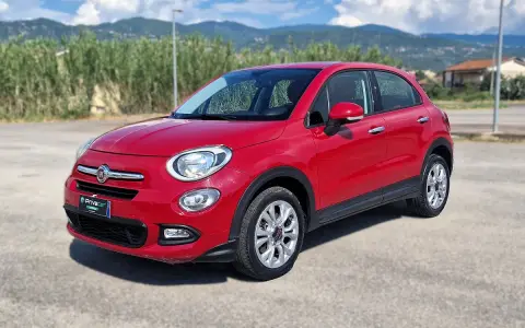 Fiat 500X rossa parcheggiata all'aperto, con montagne sullo sfondo. La pressione gomme è ottimale per ogni viaggio.