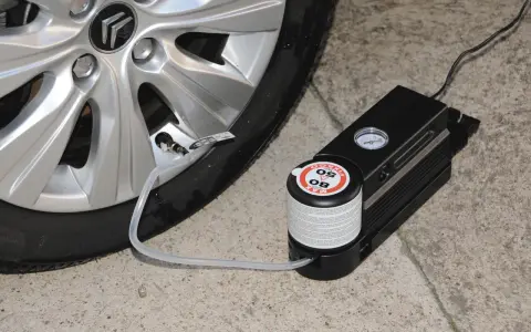 Riparazione di una gomma bucata con kit di gonfiaggio. Il compressore è collegato alla valvola del pneumatico.