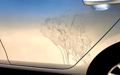Sporco e macchie sul fianco di un'auto argentata, forse dopo un trattamento di soda blasting.