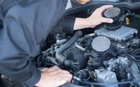 Meccanico che controlla il debimetro auto, un componente essenziale per il corretto funzionamento del motore.