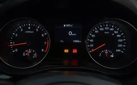 Cruscotto auto con tachimetro, contagiri e spia freno a mano accesa.