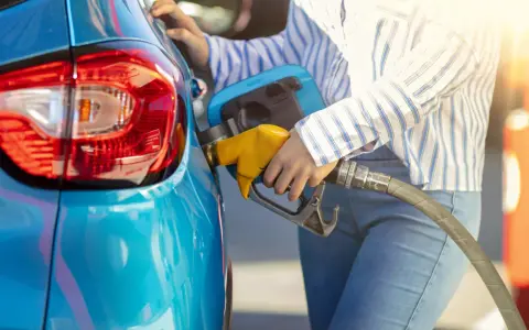 Persona fa rifornimento alla sua auto blu, pensando a come pneumatici con bassa resistenza al rotolamento migliorano l'efficienza.
