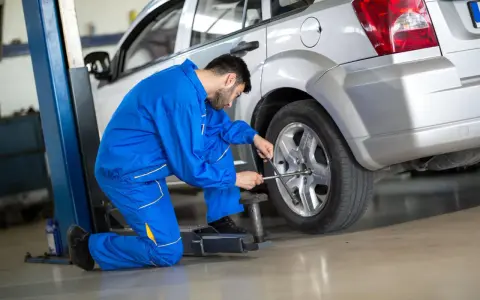 Meccanico in tuta blu lavora su una ruota, forse per montare gomme nuove davanti o dietro.