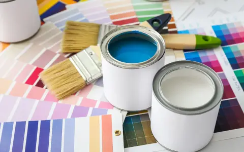 Pennelli e barattoli di vernice su campioni di colore. Una scelta di tonalità, tra cui vernice perlata o metallizzata, per il tuo prossimo progetto.