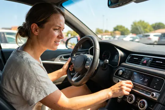 Donna frustrata al volante, tenta di regolare il climatizzatore. L'aria condizionata dell'auto non funziona, che caldo!
