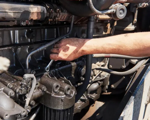 Mano con chiave inglese lavora su un motore sporco d'olio, forse per riparare cos'è l'alternatore.