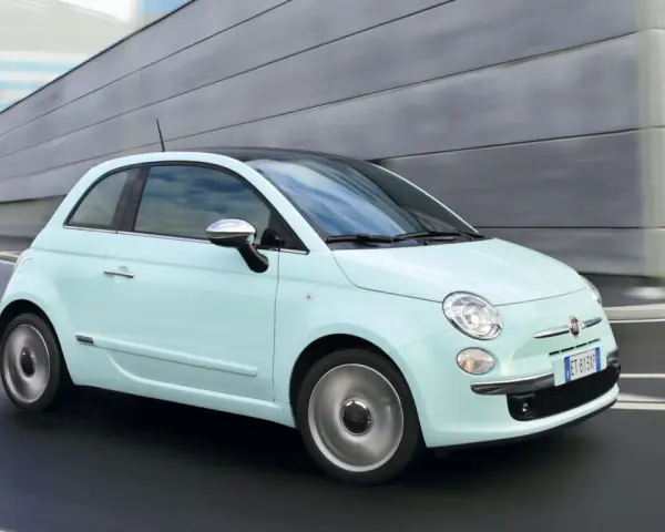 Fiat 500 azzurra in movimento, con la sua linea iconica che esprime la coppia massima di stile e agilità urbana.