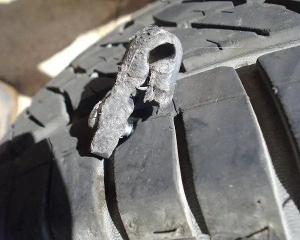 Un pezzo di gomma strappato, forse da una spalla pneumatico, è conficcato nel battistrada di un pneumatico.