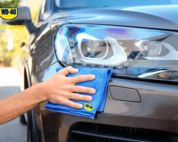 Mano che lucida fari auto con WD-40 e panno blu. Ottimo lavoro!