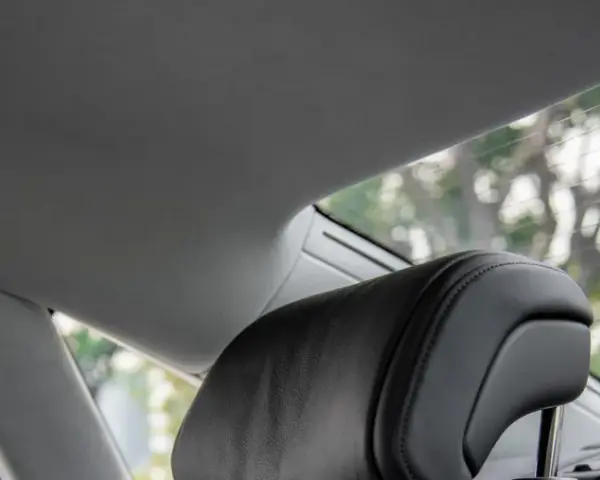 Interno auto con tettuccio grigio e poggiatesta in pelle nera. Si vede il lunotto con alberi sfocati all'esterno, come se si potesse incollare il cielo dell'auto senza smontarlo.