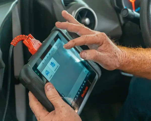Un meccanico usa uno scanner per scoprire quanto costa una diagnosi auto.
