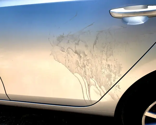 Sporco e macchie sul fianco di un'auto argentata, forse dopo un trattamento di soda blasting.
