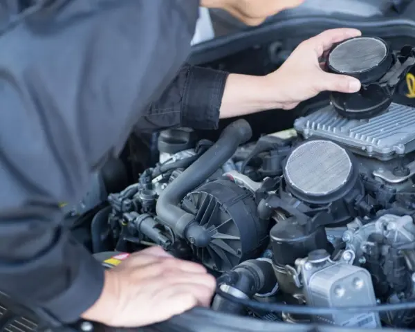 Meccanico che controlla il debimetro auto, un componente essenziale per il corretto funzionamento del motore.
