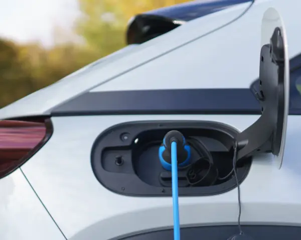 Auto elettrica in carica, con cavo blu collegato alla porta. La coppia motore è pronta per la prossima avventura.