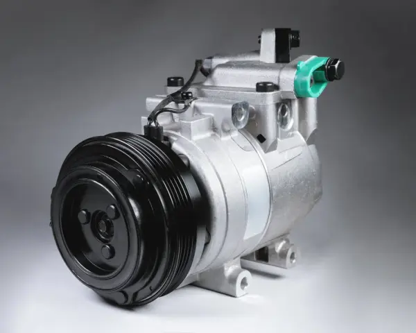 Compressore d'aria condizionata auto: scopri come funziona. Componente metallico argentato con puleggia nera.