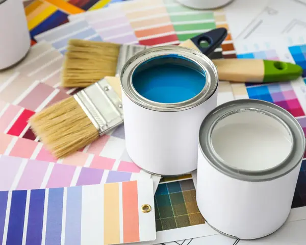 Pennelli e barattoli di vernice su campioni di colore. Una scelta di tonalità, tra cui vernice perlata o metallizzata, per il tuo prossimo progetto.