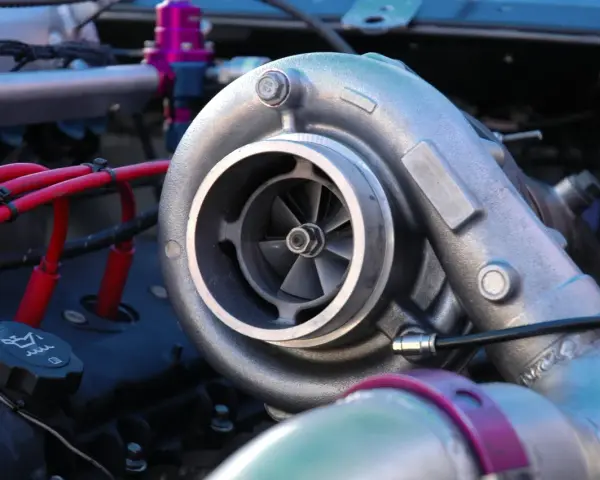 Dettaglio di un motore con un turbo benzina cromato, cavi rossi e un tappo dell'olio.
