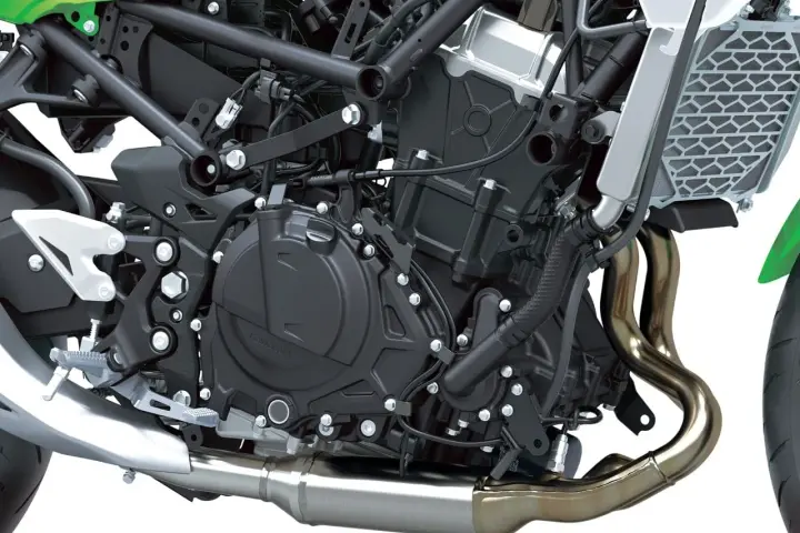 Dettaglio motore di una moto, con tubi di scarico lucidi e componenti meccanici complessi. Il freno motore è parte integrante di questo sistema.