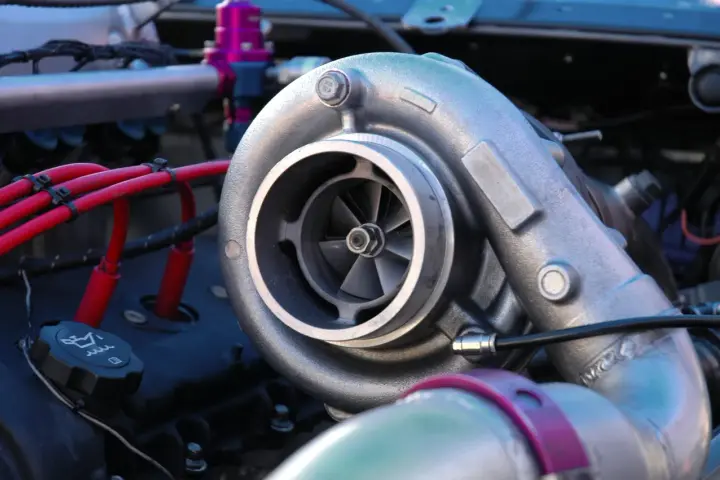 Dettaglio di un motore con un turbo benzina cromato, cavi rossi e un tappo dell'olio.