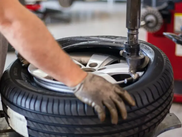 Un meccanico lavora su una gomma. La domanda su ogni quanti km si cambiano le gomme è importante per la sicurezza.