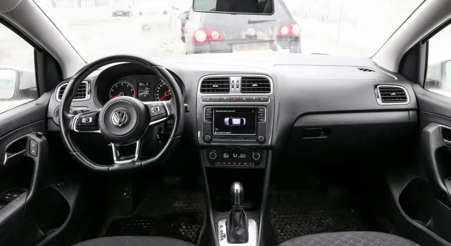 Interno di una Volkswagen Polo, con volante, cruscotto e cambio. Il display mostra il parcheggio assistito, utile per chi cerca il codice colore auto Volkswagen Polo.