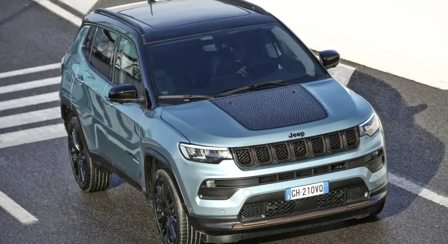 Jeep Compass color acqua con tetto nero, su strada con strisce bianche. La pressione pneumatici è ottimale per affrontare ogni percorso.
