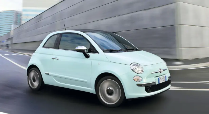 Fiat 500 azzurra in movimento, con la sua linea iconica che esprime la coppia massima di stile e agilità urbana.