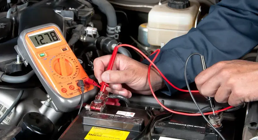 Controllo del voltaggio della batteria auto con multimetro. Il display segna 12.78V.