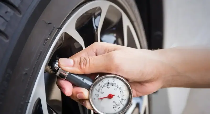 Controllo della pressione gomme 185/65 r15 con manometro. La mano tiene lo strumento attaccato alla valvola.