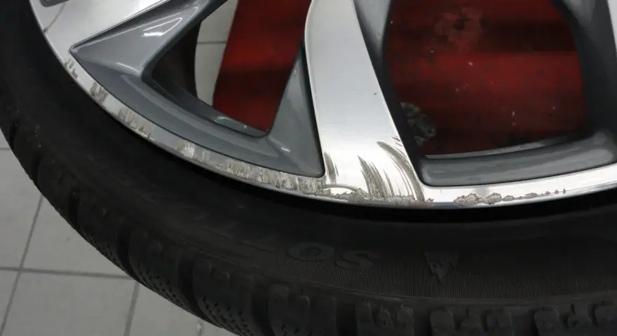 Cerchio graffiato sul marciapiede, con segni evidenti di sfregamento sul bordo metallico.