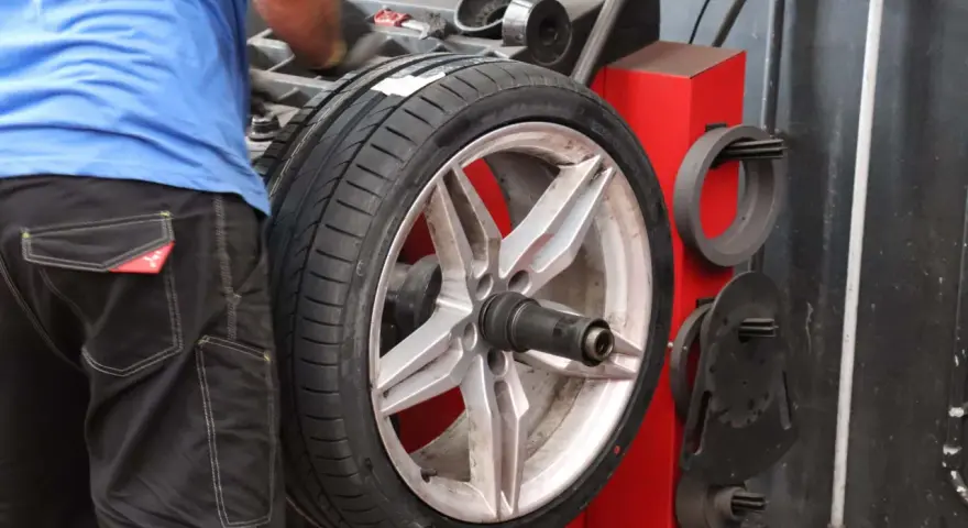 Meccanico effettua la bilanciatura gomme su un'auto sportiva. L'operazione garantisce una guida fluida e sicura.