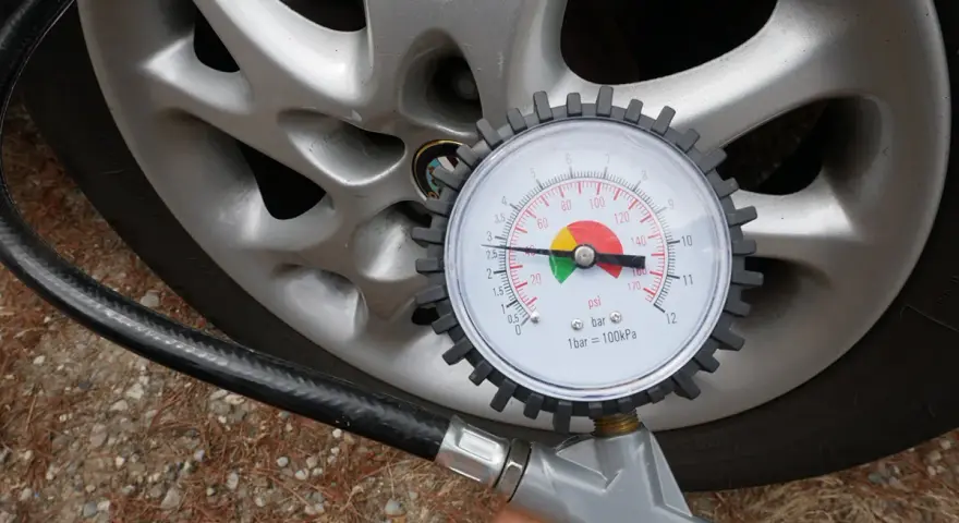 Misurazione della pressione delle gomme auto con manometro. La lancetta indica circa 2.5 bar.