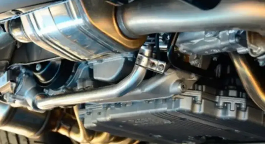 Dettaglio dell'impianto di scarico di un'auto, con tubi lucidi e silenziatore cromato.