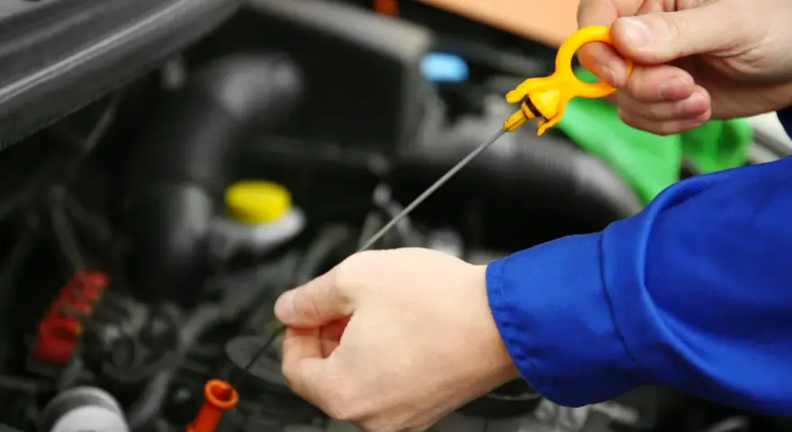Controllo livello olio motore. La mano estrae l'astina per verificare la presenza di perdita olio motore.