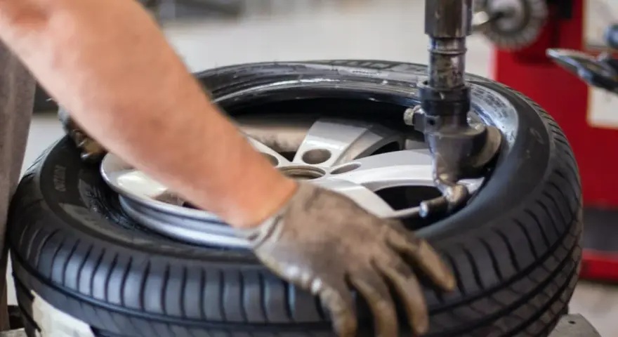 Un meccanico lavora su una gomma. La domanda su ogni quanti km si cambiano le gomme è importante per la sicurezza.