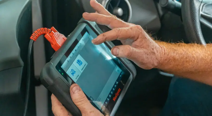 Un meccanico usa uno scanner per scoprire quanto costa una diagnosi auto.