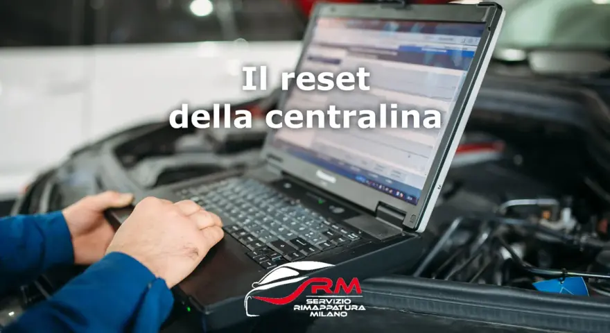 Tecnico esegue il reset centralina auto con laptop. Il logo RM Servizio Rimappatura Milano è visibile.