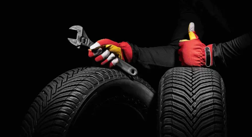 Mano guantata con chiave inglese su pneumatici, un pollice in su per pneumatici altroconsumo di qualità.