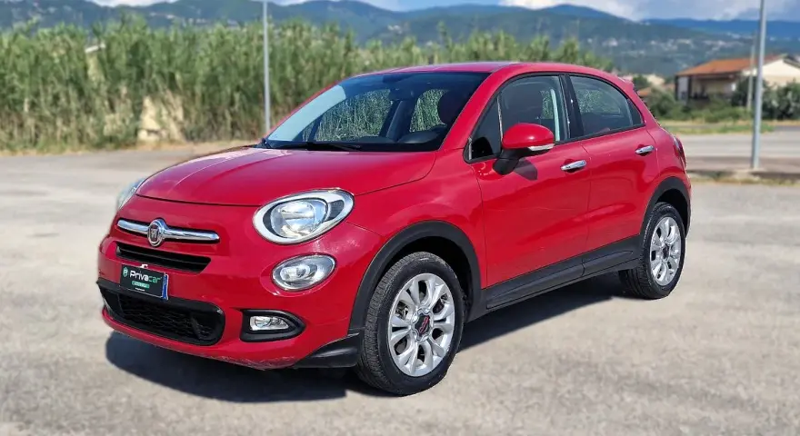 Fiat 500X rossa parcheggiata all'aperto, con montagne sullo sfondo. La pressione gomme è ottimale per ogni viaggio.