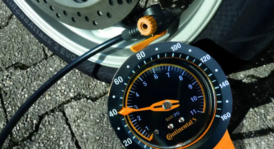 Manometro Continental per pneumatici moto, collegato alla ruota. La lancetta indica la pressione.