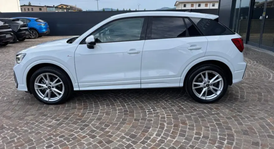 Audi Q2 bianca parcheggiata su pavé. Controlla la pressione pneumatici per un viaggio sicuro.