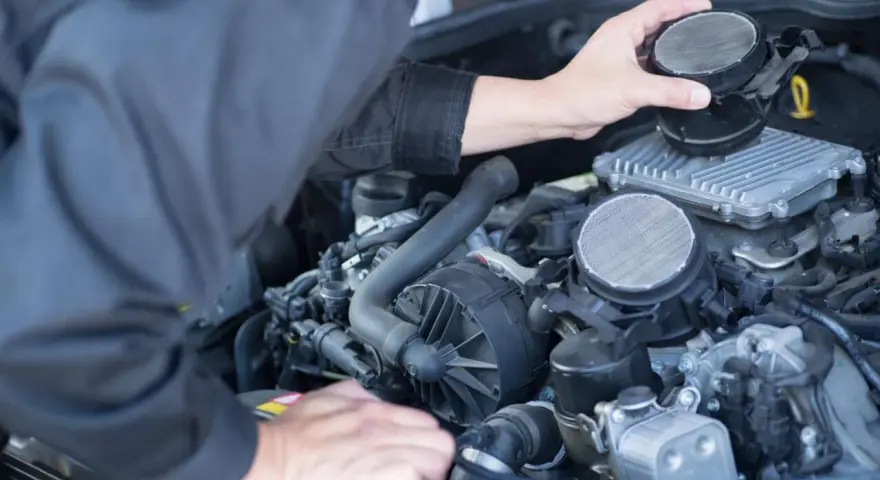 Meccanico che controlla il debimetro auto, un componente essenziale per il corretto funzionamento del motore.